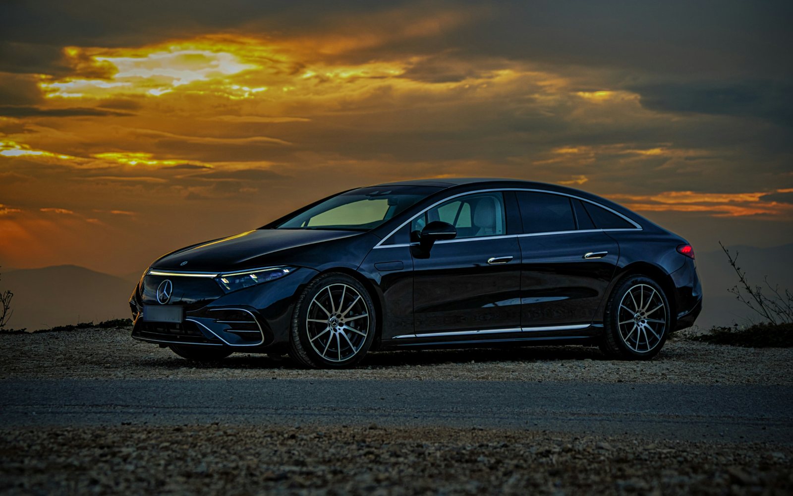 Zwarte elektrische Mercedes-Benz-sedan in de schemering, van opzij gezien.